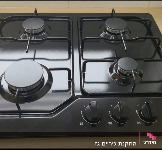 כיריים גז שחורות עם ארבעה מבערים וכפתורי שליטה
